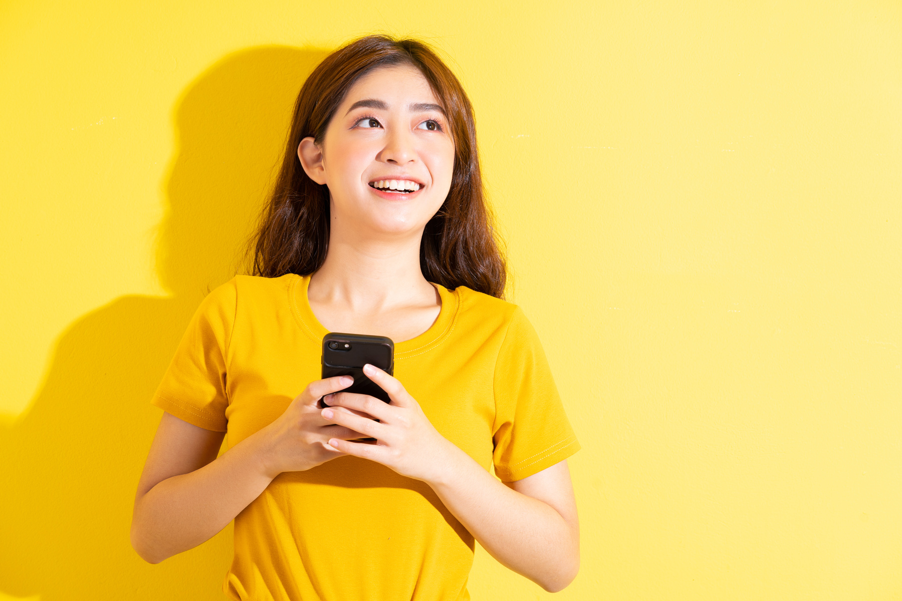 Young Asian Girl Uisng Smartphone on Yellow Background